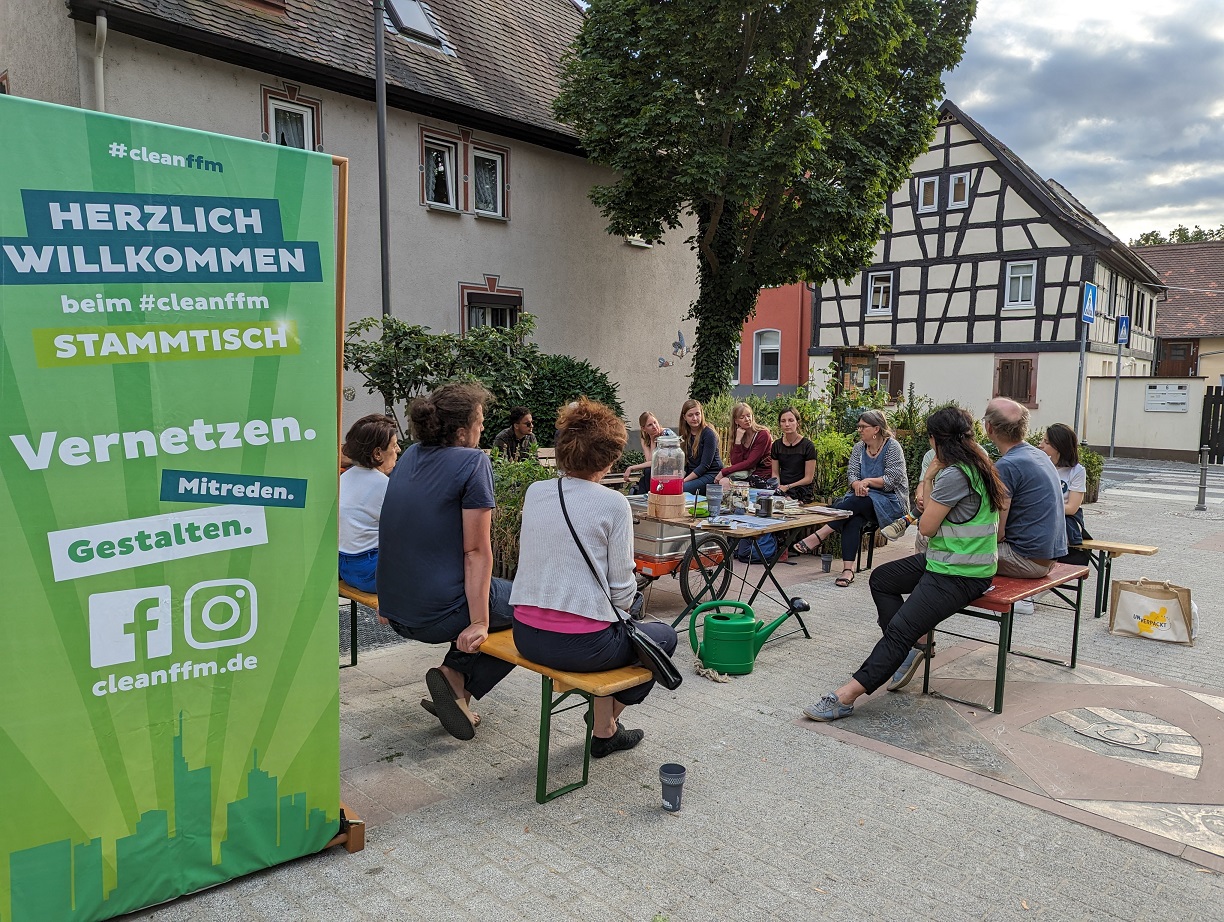 Foto: Teilnehmende einer cleanffm-Sitzung sitzen im Freien und tauschen sich aus.