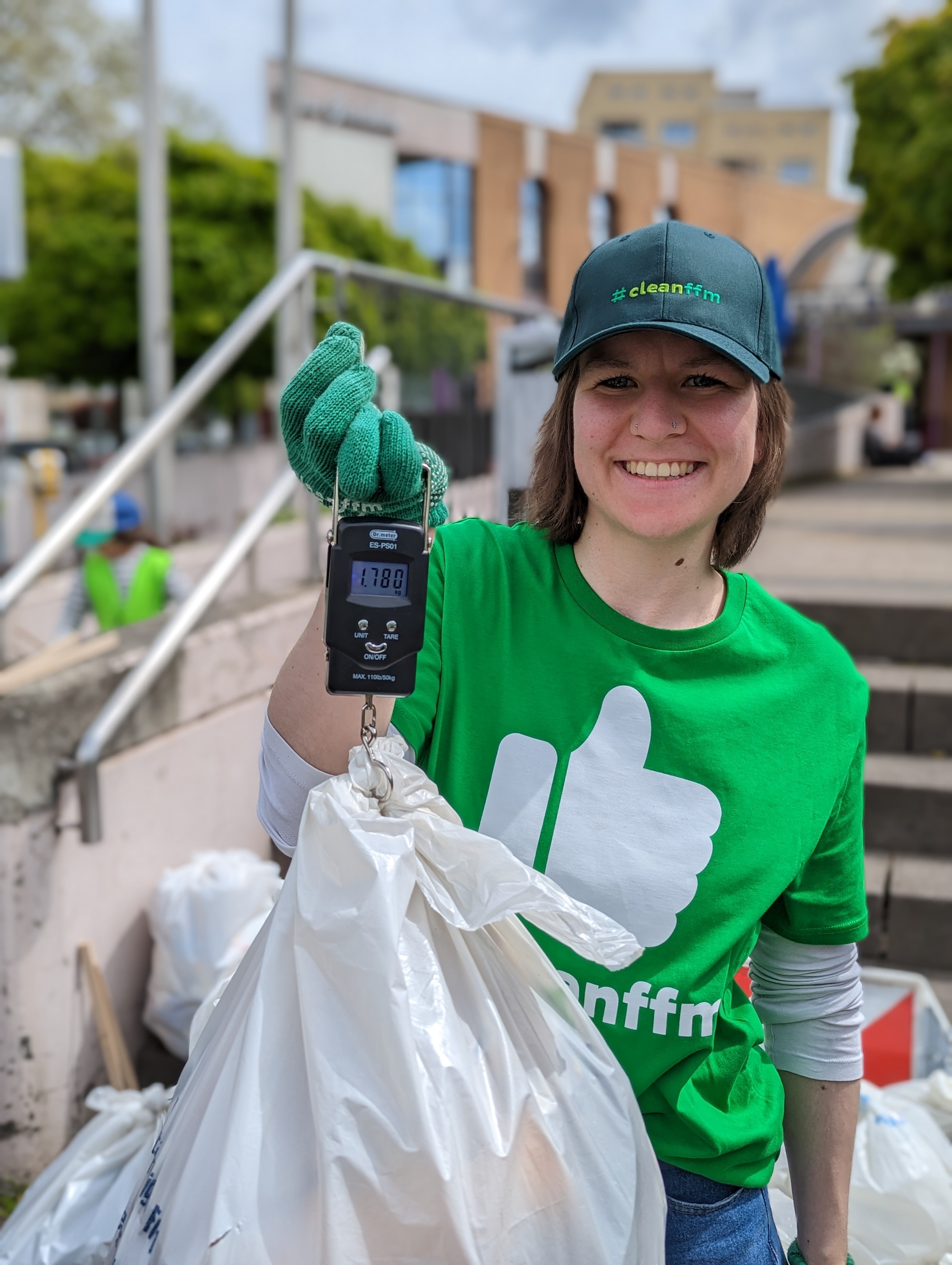 Foto: cleanffm Sauberkeitsbotschafterin hält Müllbeutel an Kofferwaage, Anzeige 1,780kg 