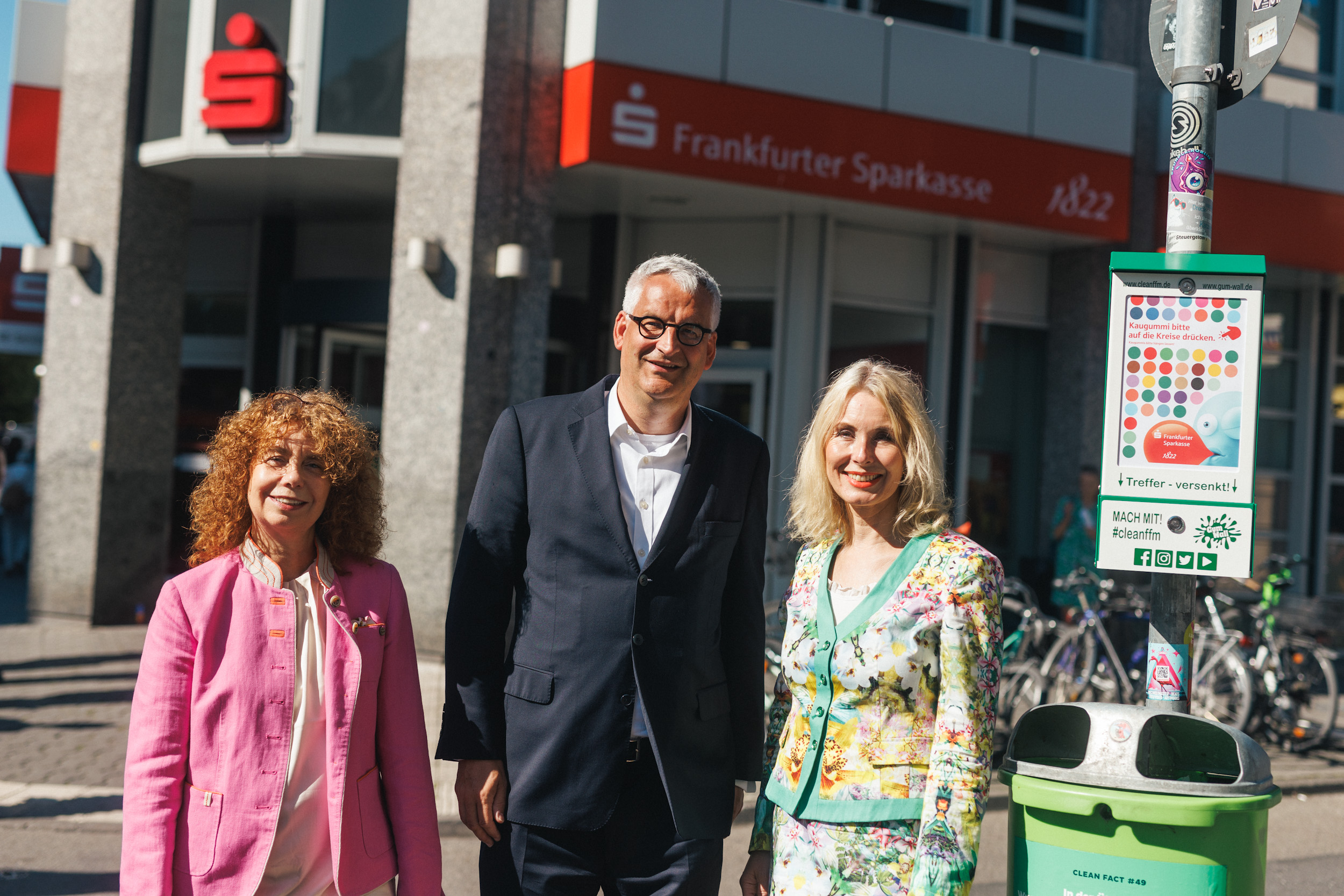 Foto: Drei Personen, darunter Stabstellenleitrin Claudia Gabriel, stehen einer Filliale der Sparkasse